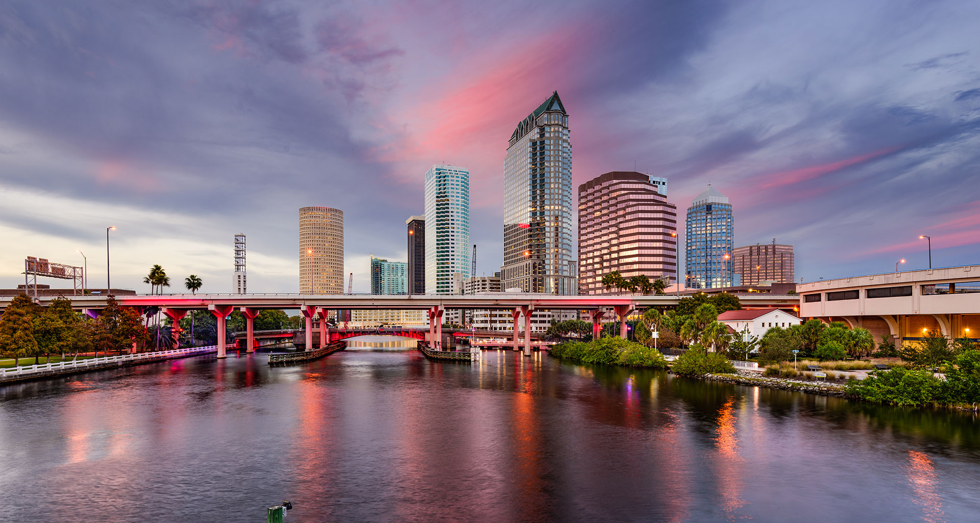 Warm bronze-toned panoramic city skyline along a river at dusk, deep amber and umber clouds with soft pink highlights, calm and elegant atmosphere
